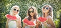 Beautiful girls with sunglasses eating fresh watermelon laughing. Happy young women holding watermelon slices outdoors Royalty Free Stock Photo