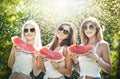 Beautiful girls with sunglasses eating fresh watermelon laughing. Happy young women holding watermelon slices outdoors Royalty Free Stock Photo