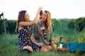 Beautiful girls tasting wine in a field near vineyard field. Celebrating successful harvest season. Couple having a romantic date