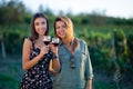 Beautiful girls tasting wine in a field near vineyard field. Celebrating successful harvest season. Couple having a romantic date Royalty Free Stock Photo