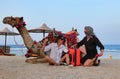 Beautiful girls-tourists are talking attentively near the camel.