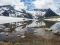 Beautiful glacial lake with springs from melting ice glacier with sharp snow-capped mountain peaks reflecting on water