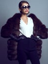 Beautiful glam model wearing white silk blouse, black pants, sable coat, leather gloves and suglasses Royalty Free Stock Photo
