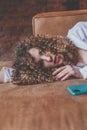 Beautiful glamorous stylish woman with curly hair lies on the sofa with green mobile phone and looking to the camera