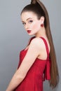 Beautiful glamorous woman fashion model with pony tail hairstyle wearing red dress and golden earring Royalty Free Stock Photo