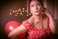 Beautiful glamour senior woman wearing red and white dress playing red baloon on lightly background