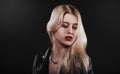 A beautiful, glamour young blond Girl dressed in a black jacket is posing on black background Royalty Free Stock Photo