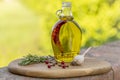 A glass cruet containing extra virgin olive oil flavored with red chili pepper is on a wooden cutting board, with garlic and rosem Royalty Free Stock Photo