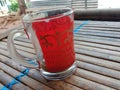 a beautiful glass that is red in color and contains delicious coffee that is just a little bit left