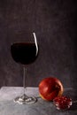 A beautiful glass with Red wine, a glass plate with pomegranate seeds and a peach on a dark background with creative Light