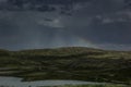 Beautiful gloomy dark stormy sky and rainbow over a green valley.