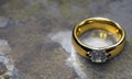 A beautiful gold diamond ring lies on a marble surface. Jewelry on the gray earth. The lost ring