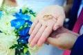 Beautiful gold rings on the palm of bride, close-up. Bride holds wedding rings on the background of a bouquet of fresh flowers. Royalty Free Stock Photo