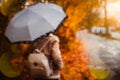 Beautiful golden autumn season. Watercolor like blurred blond girl with backpack and bright umbrella stands under rainy Royalty Free Stock Photo