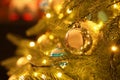 Beautiful golden Christmas ball hanging on fir tree branch against blurred background, closeup. Space for text Royalty Free Stock Photo