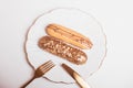 Golden colored eclairs on plate, with knife and fork