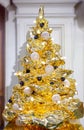 Beautiful golden foil Christmas tree with decorations and light garland. New Year, winter holidays selebration