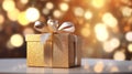 Beautiful golden gift box on the light table against blurred festive lights bokeh background Royalty Free Stock Photo