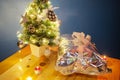 Beautiful golden lights on a tiny Christmas tree on office candle with wrapped present and candles. Christmas Eve at