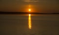 Beautiful golden orange sunset over the lake. The sun sets turning the sky yellow, orange & red tones & reflects in the lake Royalty Free Stock Photo