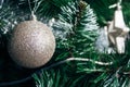 Beautiful golden sparkling ball on artificial Christmas tree. Selective focus. Holiday card with decorations for the New Year Royalty Free Stock Photo