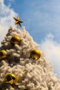 Beautiful Golden star on top of the outdoor white chrismas tree Royalty Free Stock Photo