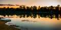 Beautiful Golden Sunset over the lake with forest reflection and a lonely boat Royalty Free Stock Photo