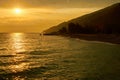 Golden sunset over sea with clouds, mountain and beach in backlight Royalty Free Stock Photo