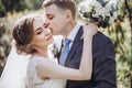 Beautiful gorgeous bride and groom kissing in sunny spring park and enjoying day. happy wedding couple relaxing in green garden. Royalty Free Stock Photo
