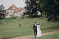 Beautiful gorgeous bride and groom walking outdoors. happy wedding couple hugging and embracing at old castle. happy romantic Royalty Free Stock Photo