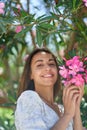 Beautiful gorgeous latina woman smiling to camera, touching pink flowers at spring garden
