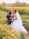 Beautiful gorgeous redhair bride and stylish handsome groom posing in a sunflower sunny field Royalty Free Stock Photo