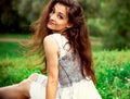 Beautiful gorgeous romantic woman with long hair sitting on the grass and looking on summer green background. Closeup Royalty Free Stock Photo