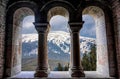 Beautiful gothic medieval arched stone window. Magnificent majestic view from the window. Winter mountains and a castle Royalty Free Stock Photo