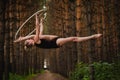 Beautiful and graceful aerial gymnast does exercises on the ring in the forest Royalty Free Stock Photo