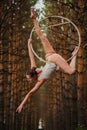 Beautiful and graceful aerial gymnast does exercises on the ring