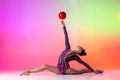 Beautiful, graceful sport. Young sportive girl, rhythmic gymnast in twine with red ball isolated on colored neon