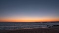 Beautiful gradient sky on beach at sunset in Portugal. Silhouetted people walking dog at shoreline. Royalty Free Stock Photo