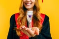 Beautiful graduate holds an hourglass in her hand on an isolated yellow background