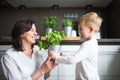 Beautiful grandmother with little boy spending together time in kitchen, learning to cook. Grandson with potted herb in