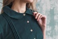 Beautiful green corduroy dress on a girl close-up. Hand on the collar