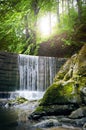 Beautiful green countryside. Waterfall on a river with big rocks and deciduous forest. Green landscape.