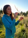 A beautiful girl in a field playing with plants. The concept of walking in nature, freedom and an eco-friendly lifestyle Royalty Free Stock Photo