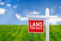 Beautiful green field and blue sky with LAND FOR SALE sign. Royalty Free Stock Photo