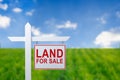 Beautiful green field and blue sky with LAND FOR SALE sign. Royalty Free Stock Photo