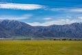 Beautiful green field with lush trees and snowy mountains in the background taken on a sunny day, New Zealand Royalty Free Stock Photo