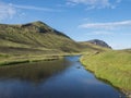 Beautiful green hills, lush grass and blue river next to camping site on Alftavatn lake. Summer sunny day, landscape of Royalty Free Stock Photo