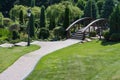 Beautiful green lane with pathway and wooden bridge among trees. Spring and summer park with empty road. Garden decoration. Royalty Free Stock Photo