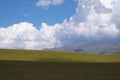 Beautiful green mountain valley with blue cloudy sky on background. Spring farm field landscape. Outdoor landscape. Sunset light. Royalty Free Stock Photo
