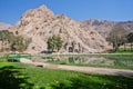 Beautiful green park with lake, montains and historical site - Arches of Taq-e Bostan, Iran.